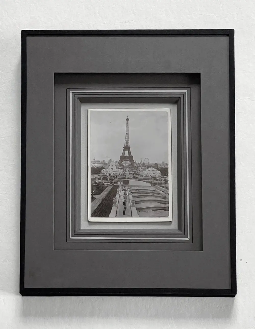 encadrement-exemple Encadrement sur mesure d'une carte postale ancienne illustrant la tour Eiffel, mise en valeur sous verre avec jeux de profondeur et harmonie de tons gris, noir et blanc.