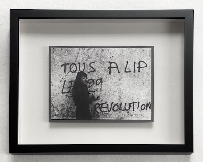 Photographie vintage en noir et blanc encadrée en cadre boîte, avec graffiti sur un mur en arrière-plan