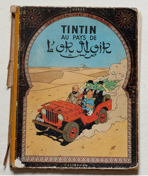 Album Tintin au pays de l’or noir avant restauration, avec dos fortement endommagé, toile décollée et bords de couverture usés.