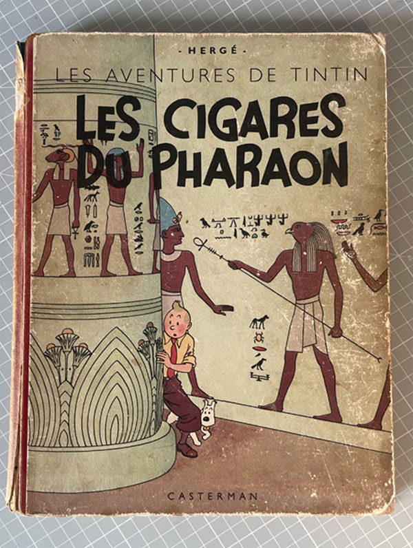 Album Tintin ancien Les Cigares du Pharaon d’Hergé, édition Casterman de 1943, avant restauration : couverture illustrée présentant des frottements, des coins usés et des dégradations sur les bords.